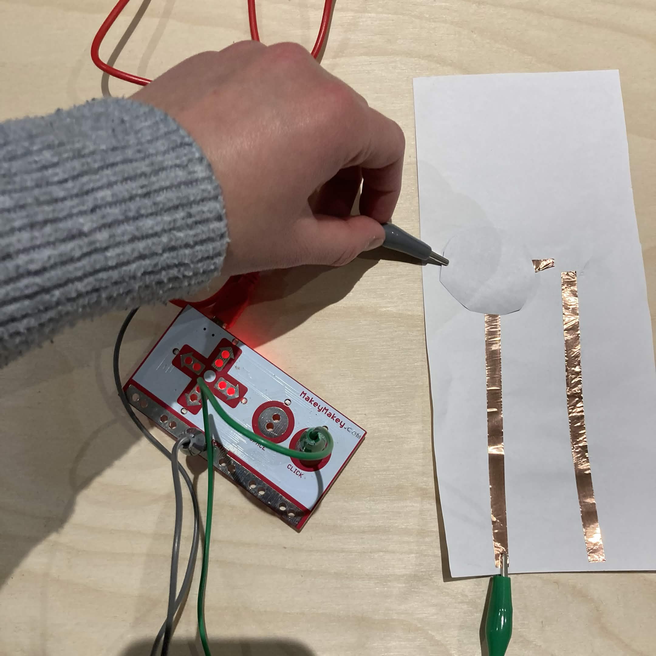 Using the graphite circle to connect the circuit and trigger the Makey Makey