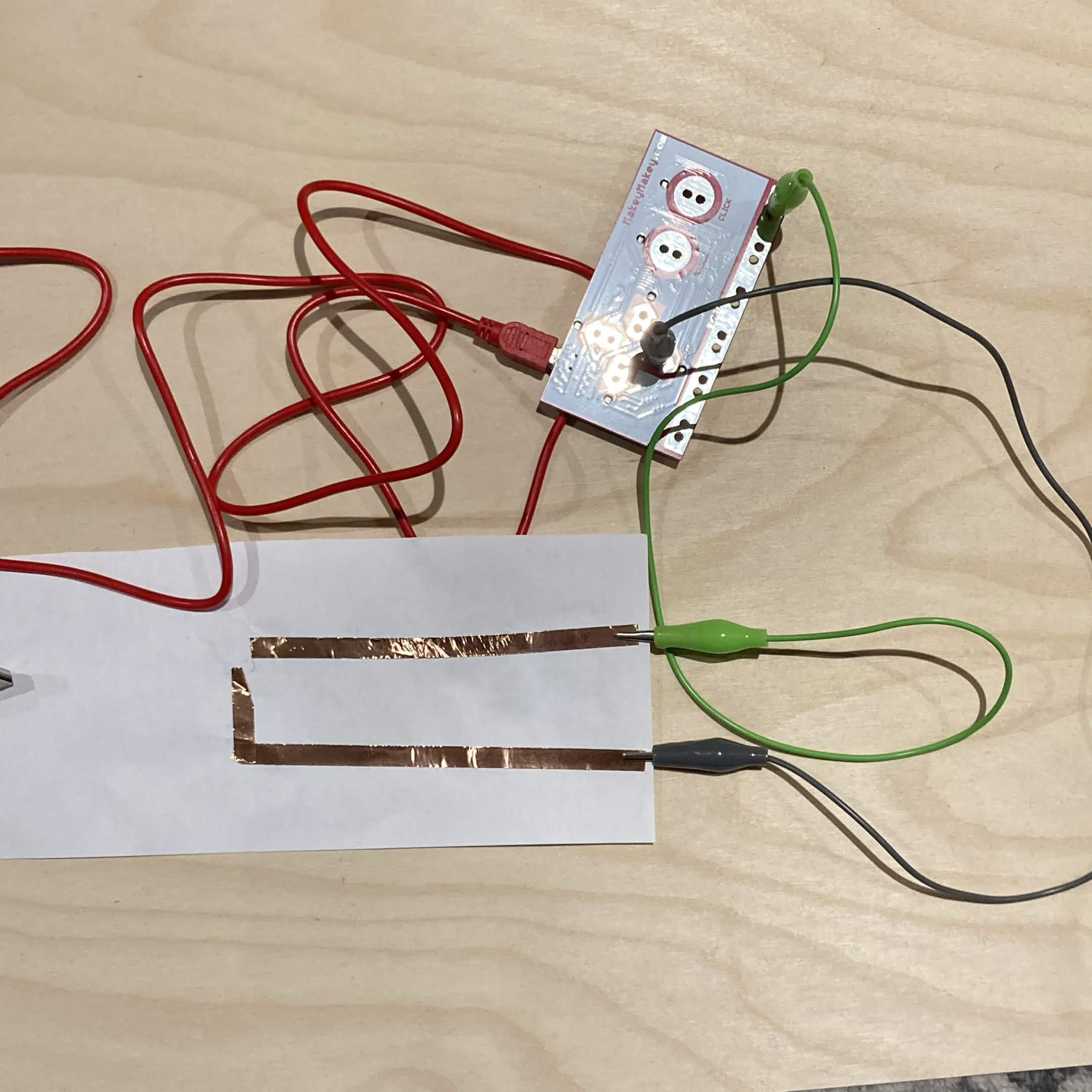 This copper tape circuit requires the user to place their finger on the corner to connect both lines of tape and trigger the Makey Makey function